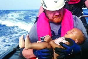 منقذ يحمل طفلاً ميتاً قذفته أمواج البحر على السواحل الإيطالية بعد غرق قارب خشبي الأسبوع الماضي | رويترز